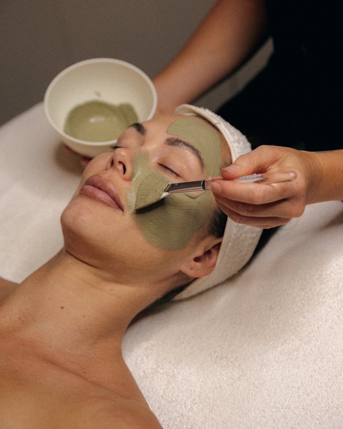 Esthetician applying a green mask during a facial treatment at LADA Beauty studio, serving El Paso, TX