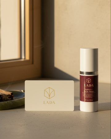 LADA Beauty Hydra-C+ Serum in a white bottle with burgundy label on a windowsill, skincare for Las Cruces, NM and El Paso, TX