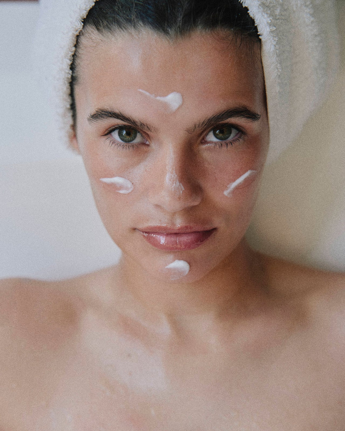 woman in white towel with moisturizer on her face for LADA beauty skincare brand